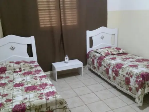 Quarto com duas camas de cabeceira branca e colchas floridas