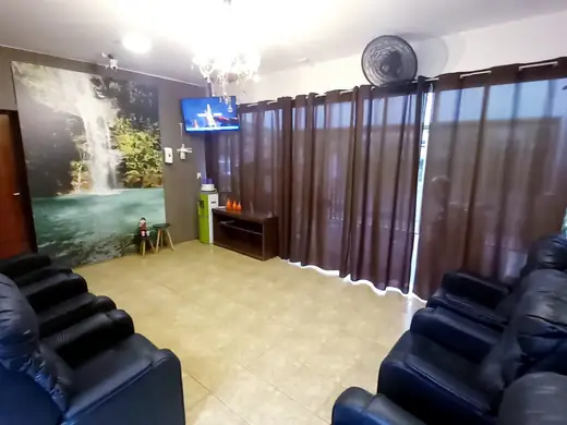 Sala com poltronas reclináveis, cortinas marrons e painel de cachoeira na parede