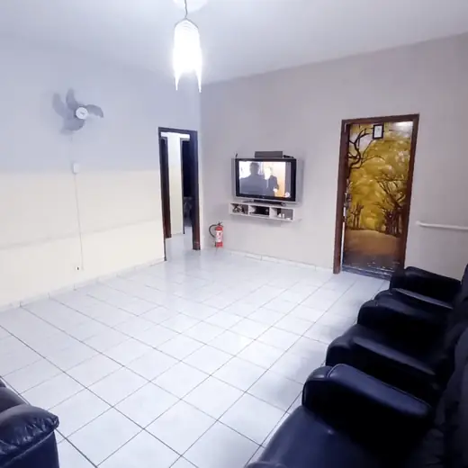 Sala clara com poltronas reclináveis, TV e porta com painel de árvore